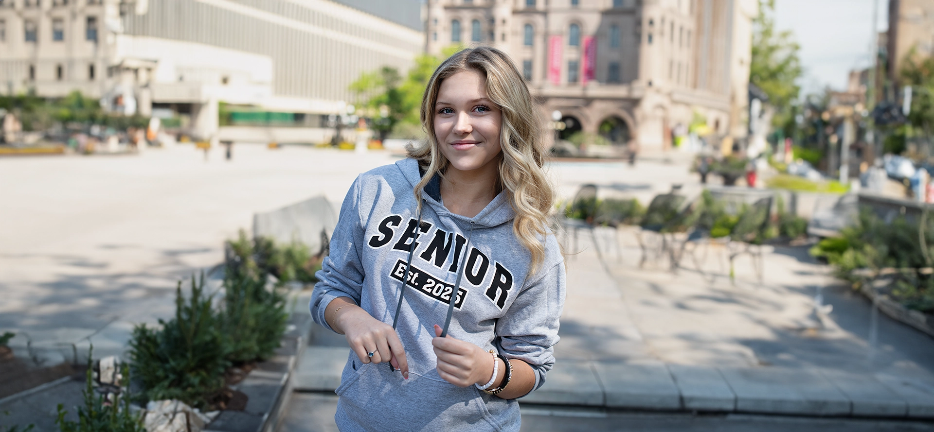 A woman in grey hoodie standing on street.