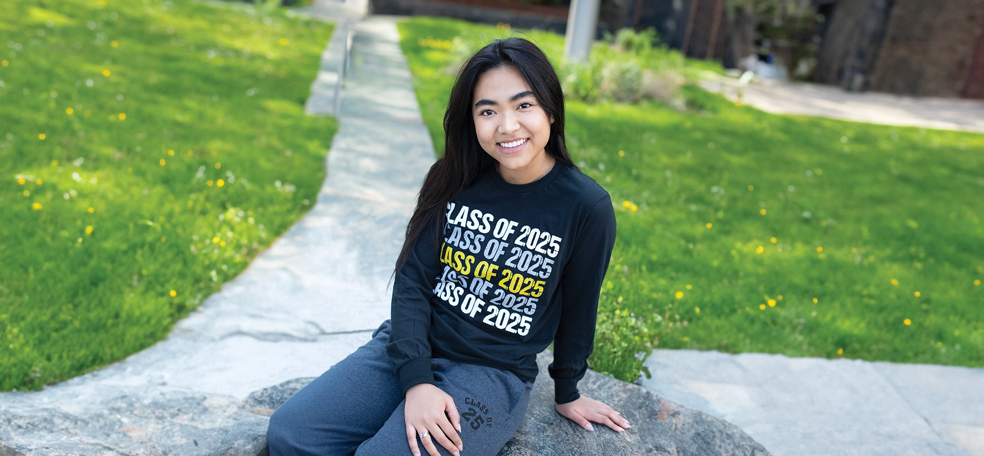 A girl sitting on the ground wearing a class of 2 0 2 5 shirt.