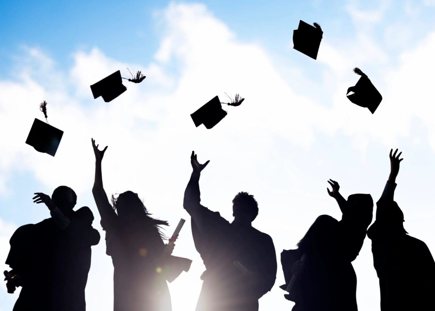 A group of people that are throwing their graduation hats in the air.