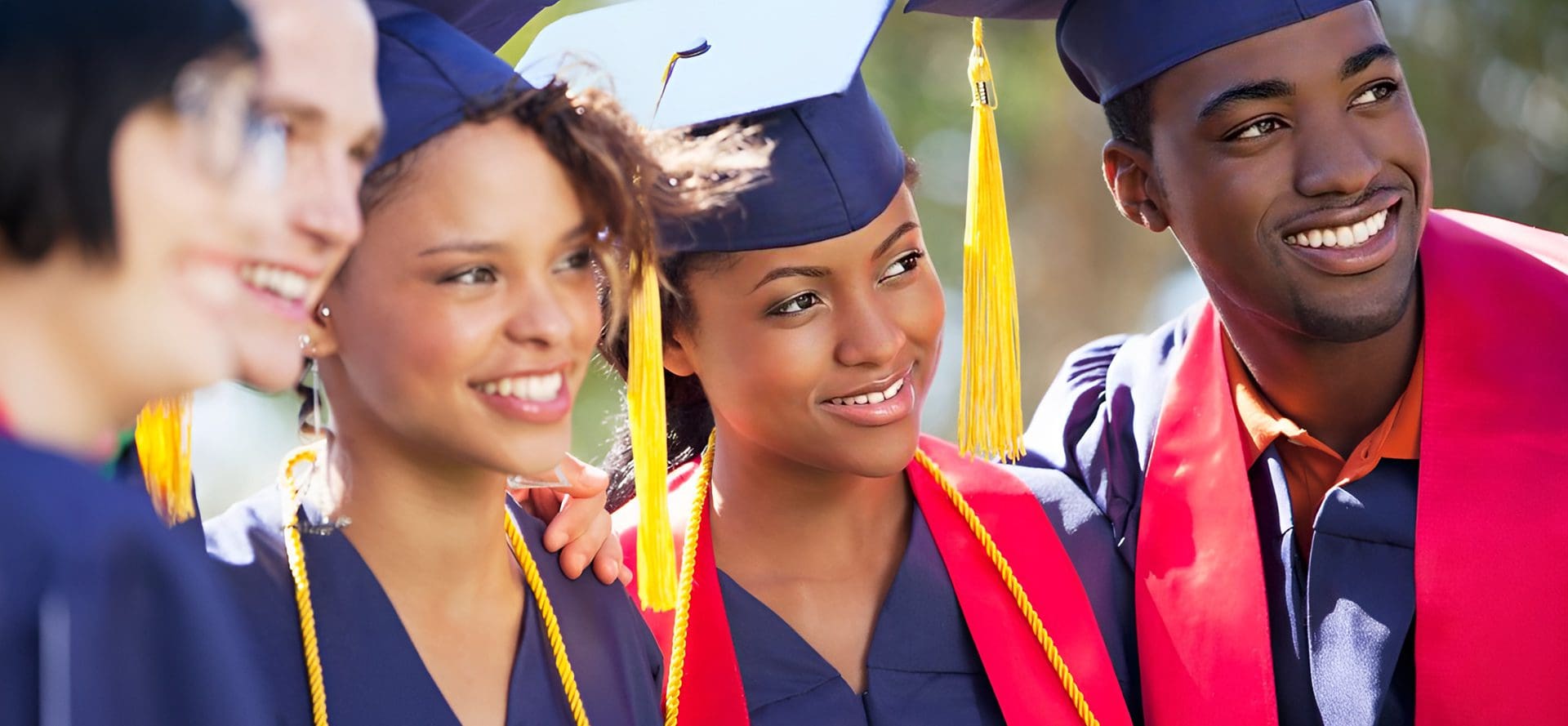 Two women in caps and gowns smile for a picture.