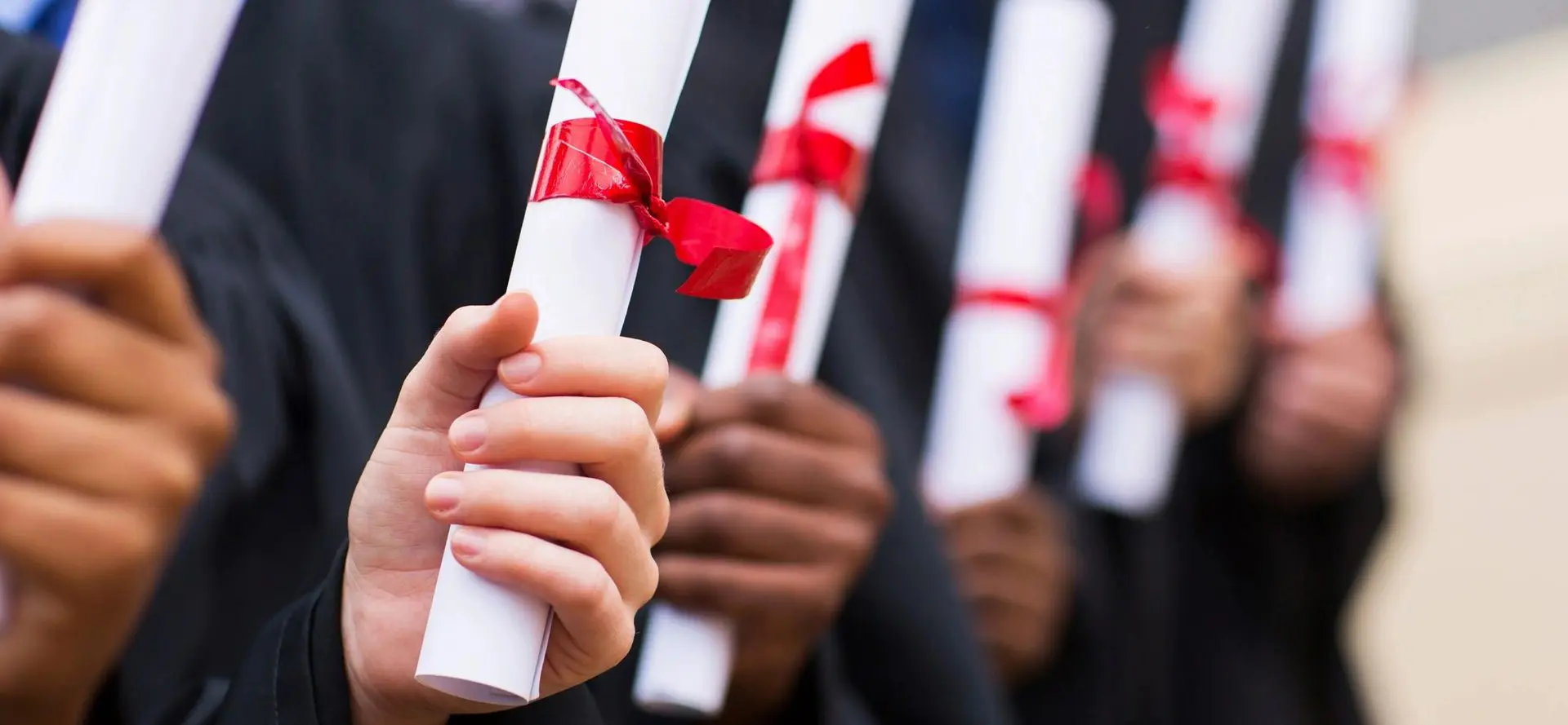 A group of people holding up their diplomas.