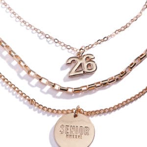 Three layered gold necklaces with unique pendants on each chain.